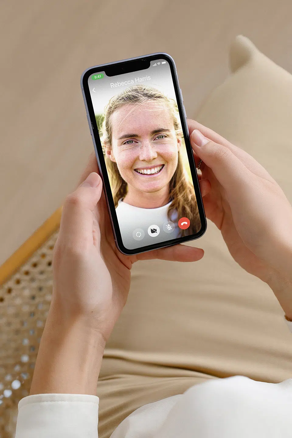 Woman holding phone showing a smiling coach on a video call